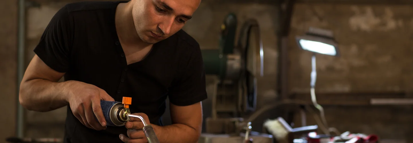 Person bearbeitet Holz mit Gasbrenner